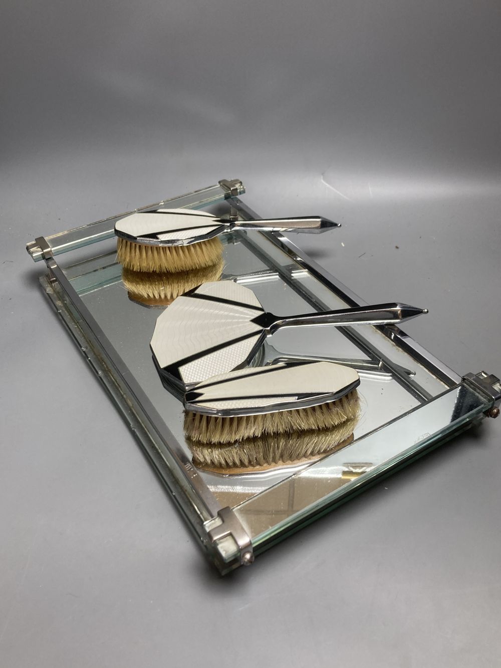 An Art Deco mirrored glass dressing table tray, 40 x 24cm and three Art Deco chrome plated dressing utensils